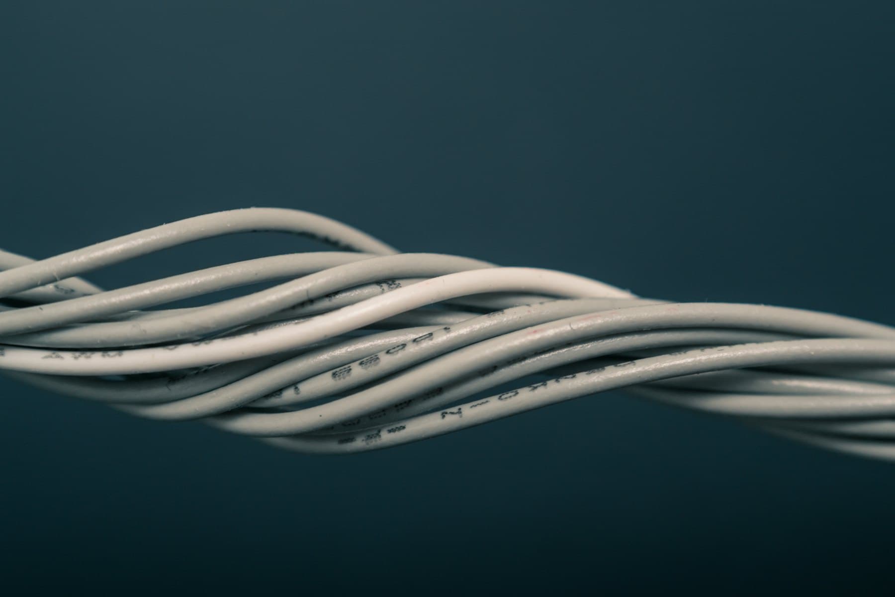 Bundle of heavy-gauge cable, twisted and lit against a dark ground.