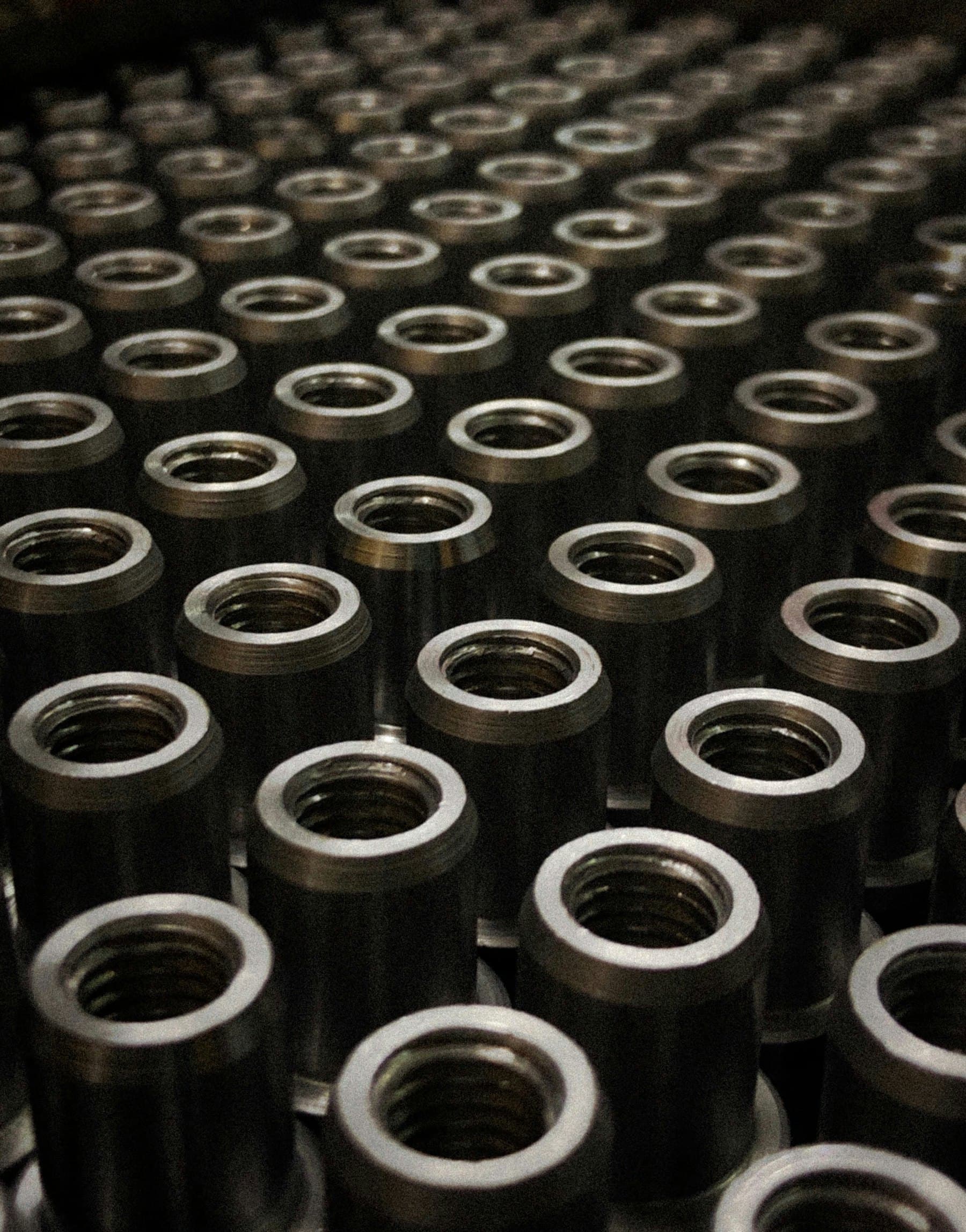 Rows of identical machined steel bushings.