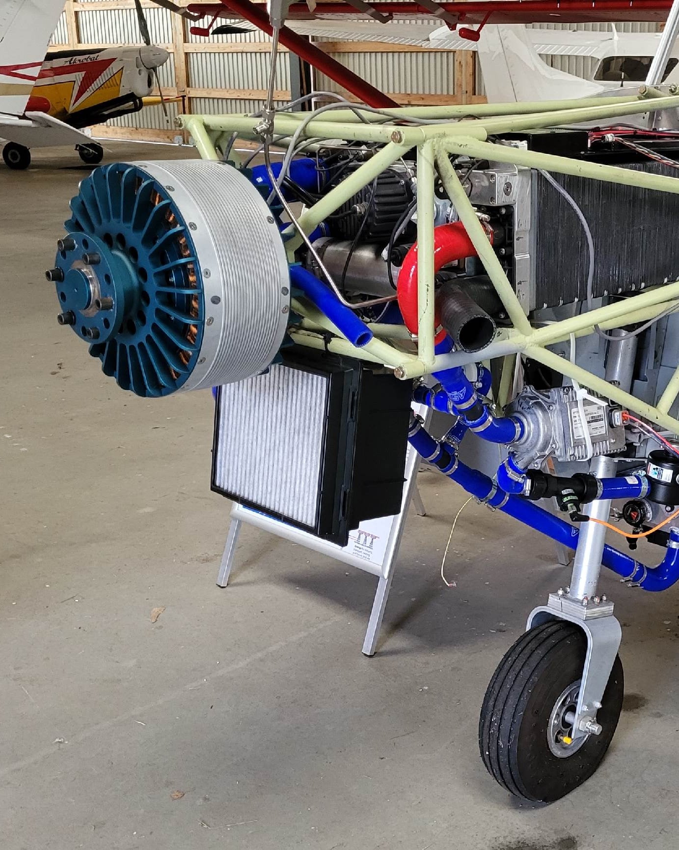 The programme aircraft in the hangar with its nose open: electric motor, cooling hoses and the structure behind them.