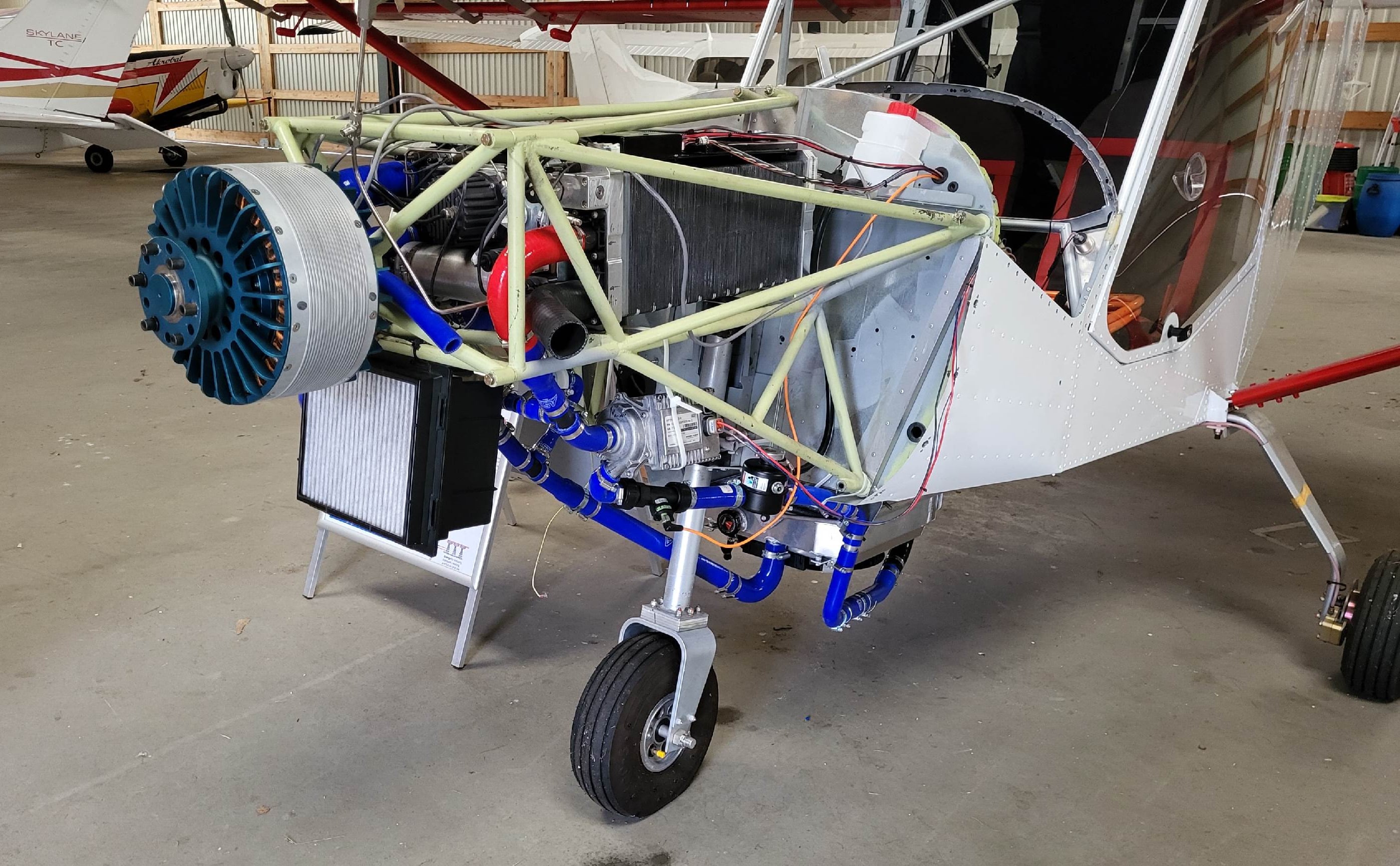 The programme aircraft in the hangar with its nose open, showing the electric motor, cooling hoses and the structure behind them.