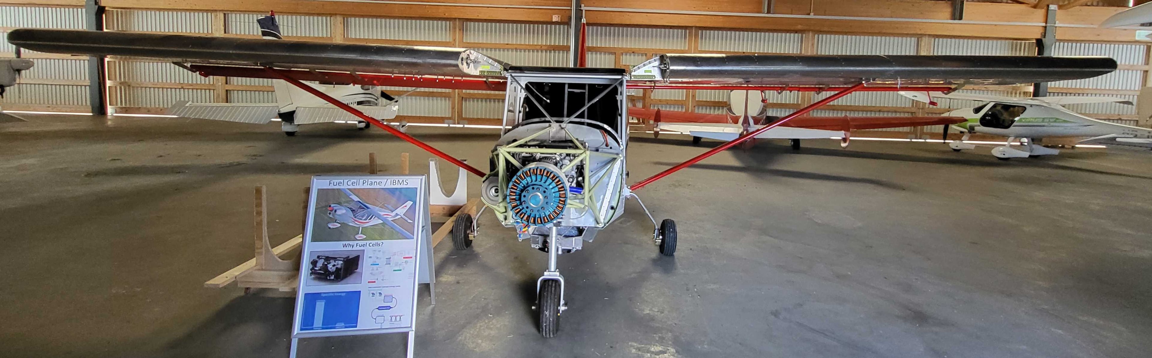 The programme aircraft in the hangar, seen head-on with its wings spread and the electric motor exposed at the nose.