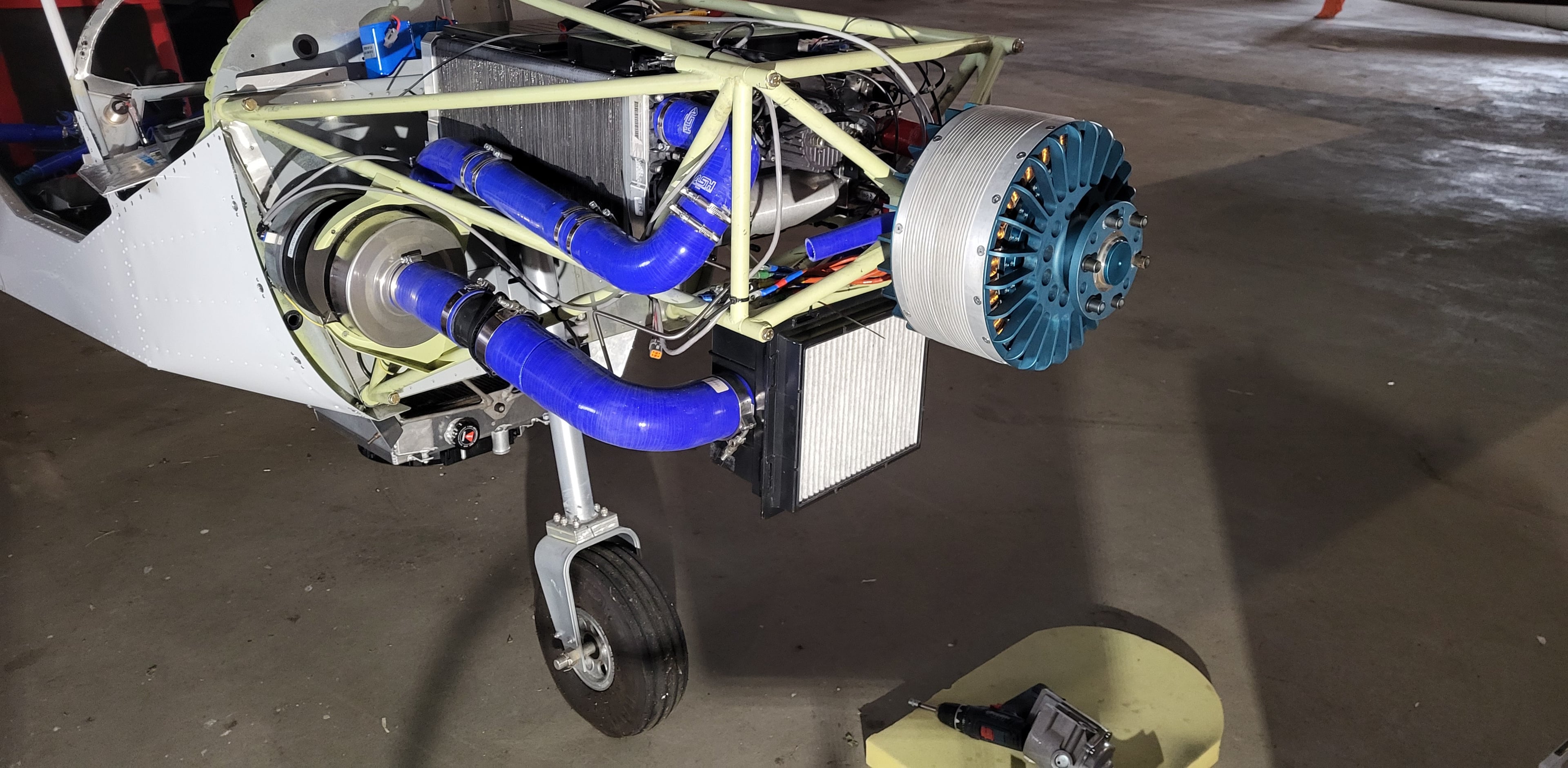 Electric motor on the nose of the programme aircraft, with its cooling hoses and radiator exposed.