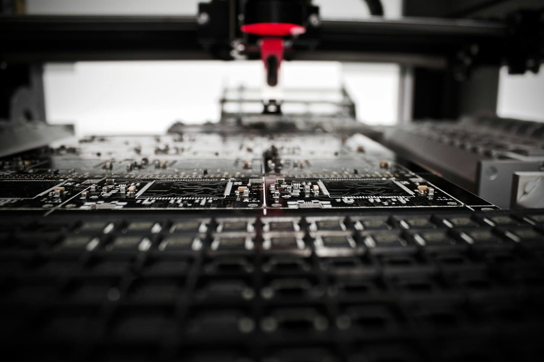 Pick-and-place head working over a panel of populated circuit boards.